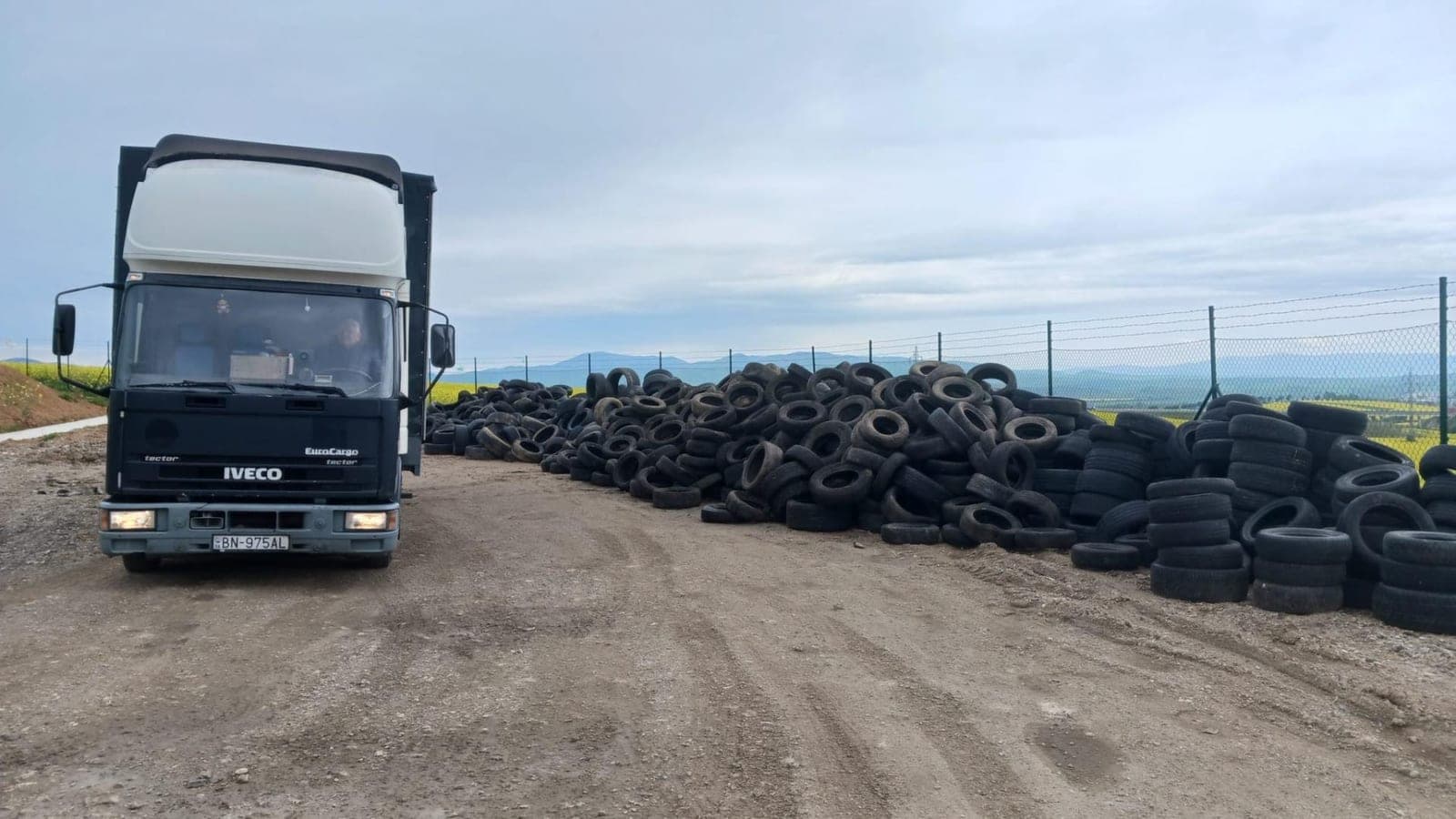 Nákladní auto u hromady starých pneumatik